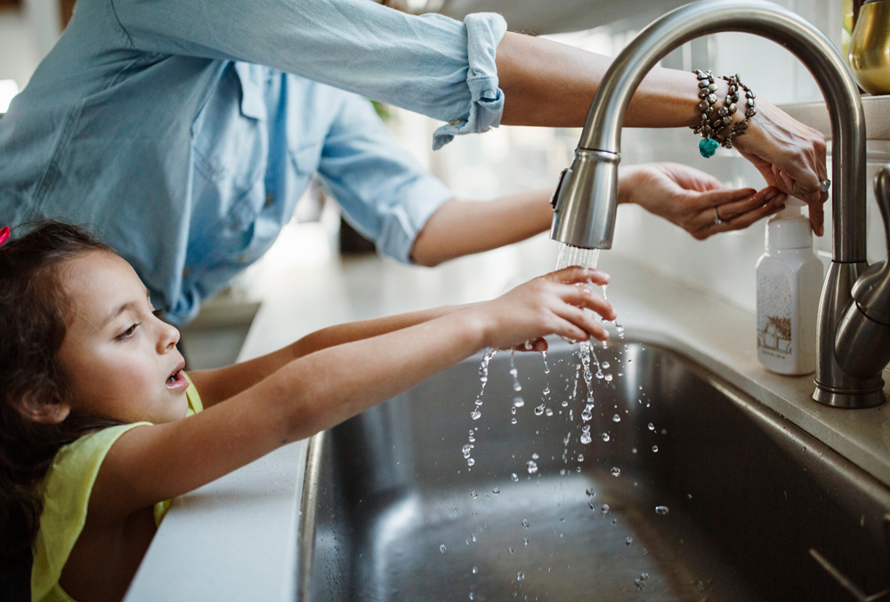 parent and child washing hands at kitchen sink