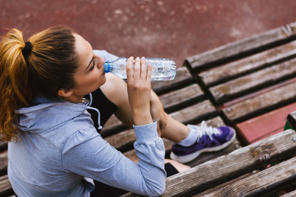 woman drinking bottled water after exercising