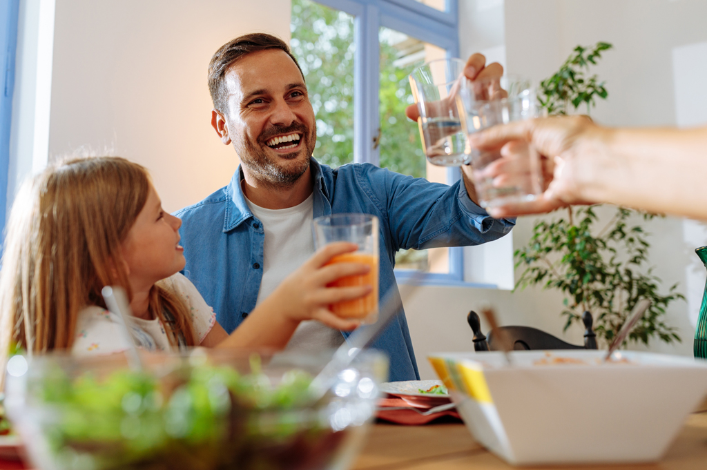 family at a kitchen table toasting glasses