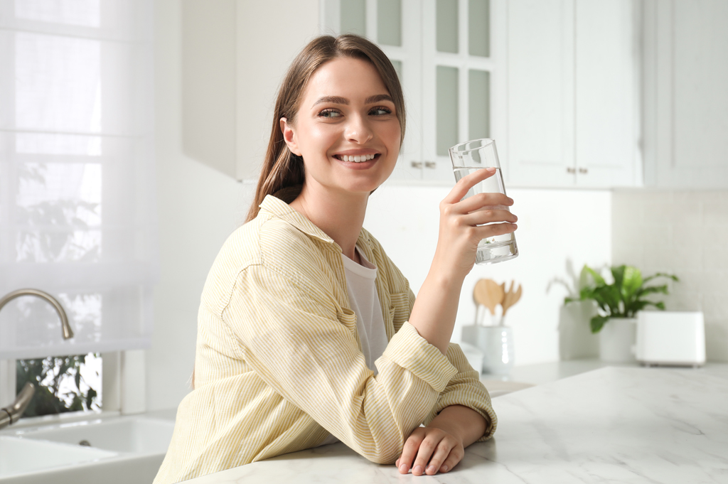 Woman drinking water from glass in modern kitchen